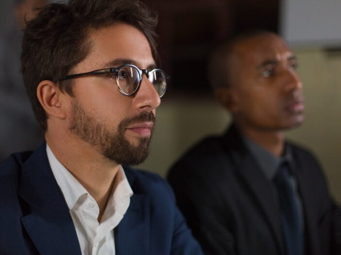 Businessman in eyeglasses working in dark office. Close-up view of serious multiethnic business colleagues working late at night, selective focus. Working late concept